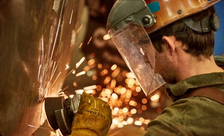 Worker wearing a face shield while operating a grinder