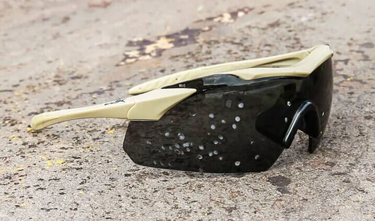 A pair of ballistic-rated safety glasses laying in the sand
