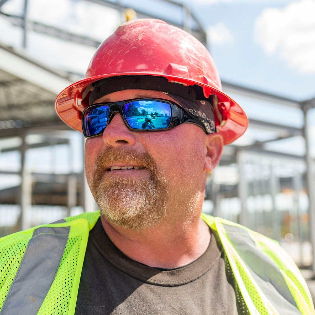 Pyramex SB5665D Goliath Safety Glasses with Black Frame and Ice Blue Mirror Lenses worn by construction worker with red hard hat and reflective safety vest