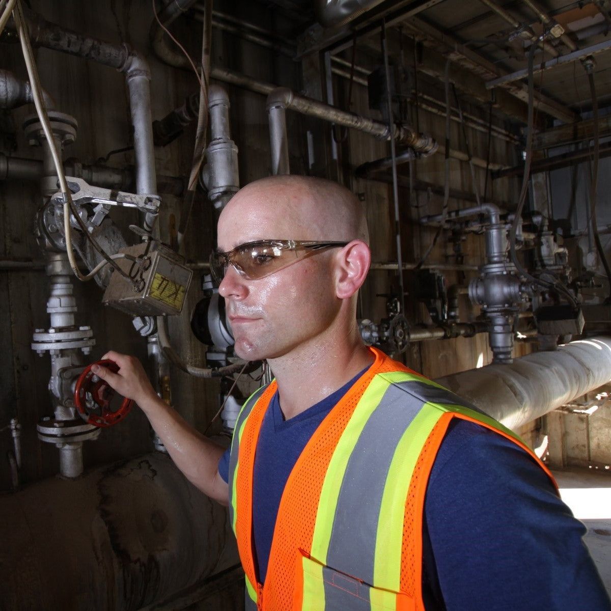 Pyramex SB7138S PMXSLIM Safety Glasses Black Temples Sandstone Bronze Lens worn by worker wearing hi-vis safety vest and operating machinery