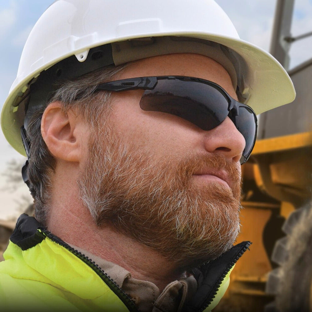 Radians Thraxus Safety Glasses with Smoke Lens worn by worker with White Hard Hat