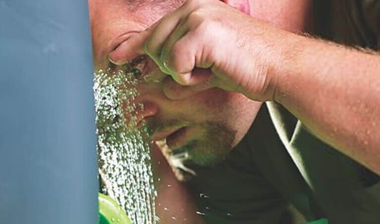 Worker flushing their eye at an emergency eyewash station