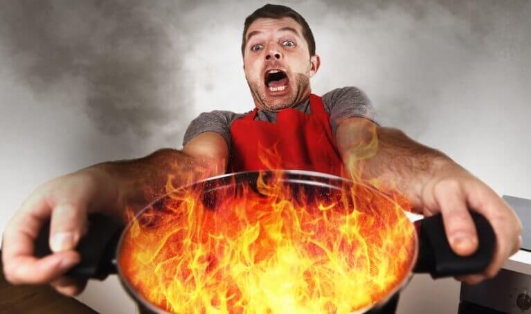 Man holding a flaming cooking pot