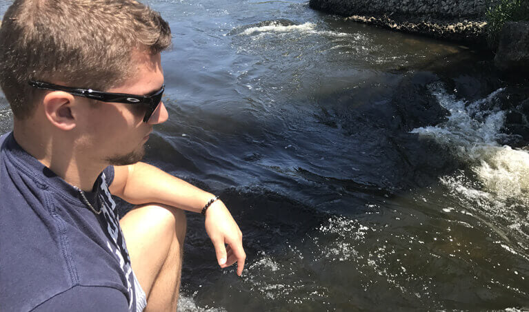 A man wearing sunglasses near a river