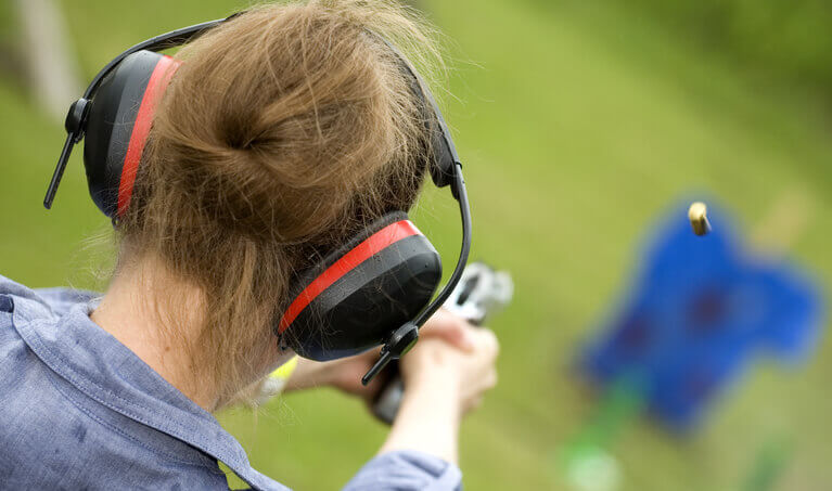 Woman wearing earmuffs while target shooting