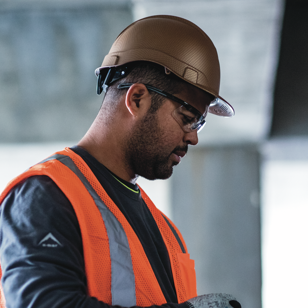 Pyramex Ridgeline Hydro Dipped Cap Style Hard Hat with 4-Point Ratchet Suspension Copper Pattern, worn by a worker with an RVZ2120 safety vest