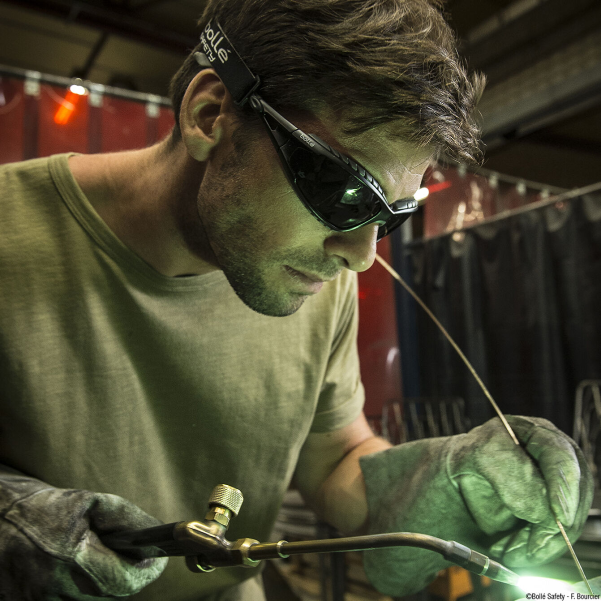 Worker wearing Bolle 40089 Tracker Safety Glasses with Black Frame and IR Shade 5 Lenses with stick welding